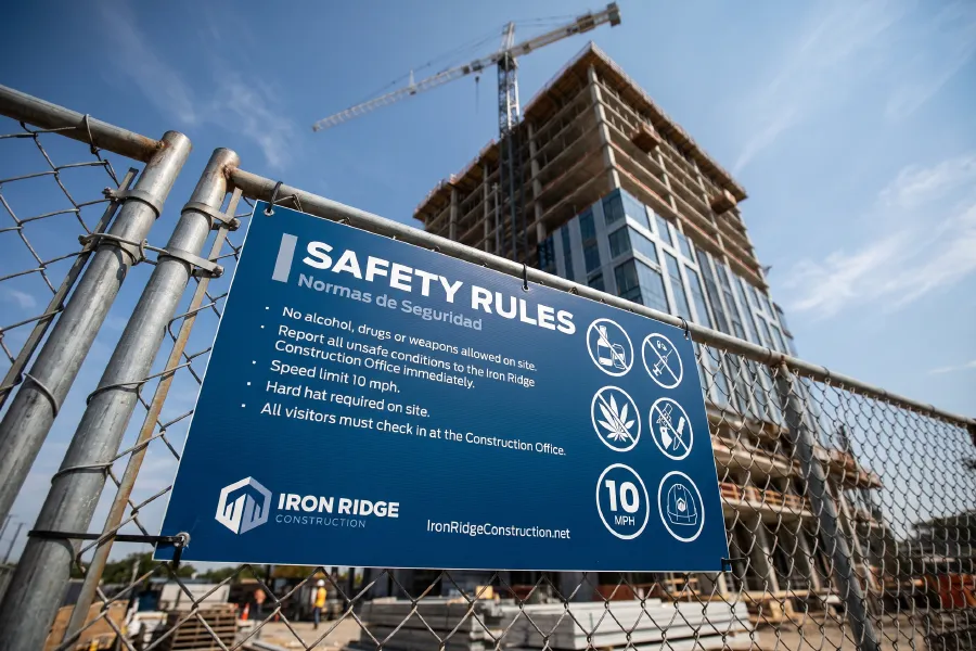 A jobsite sign on a chain link fence